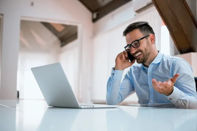 businessman-using-a-computer-talking-on-the-mobile-phone-640w